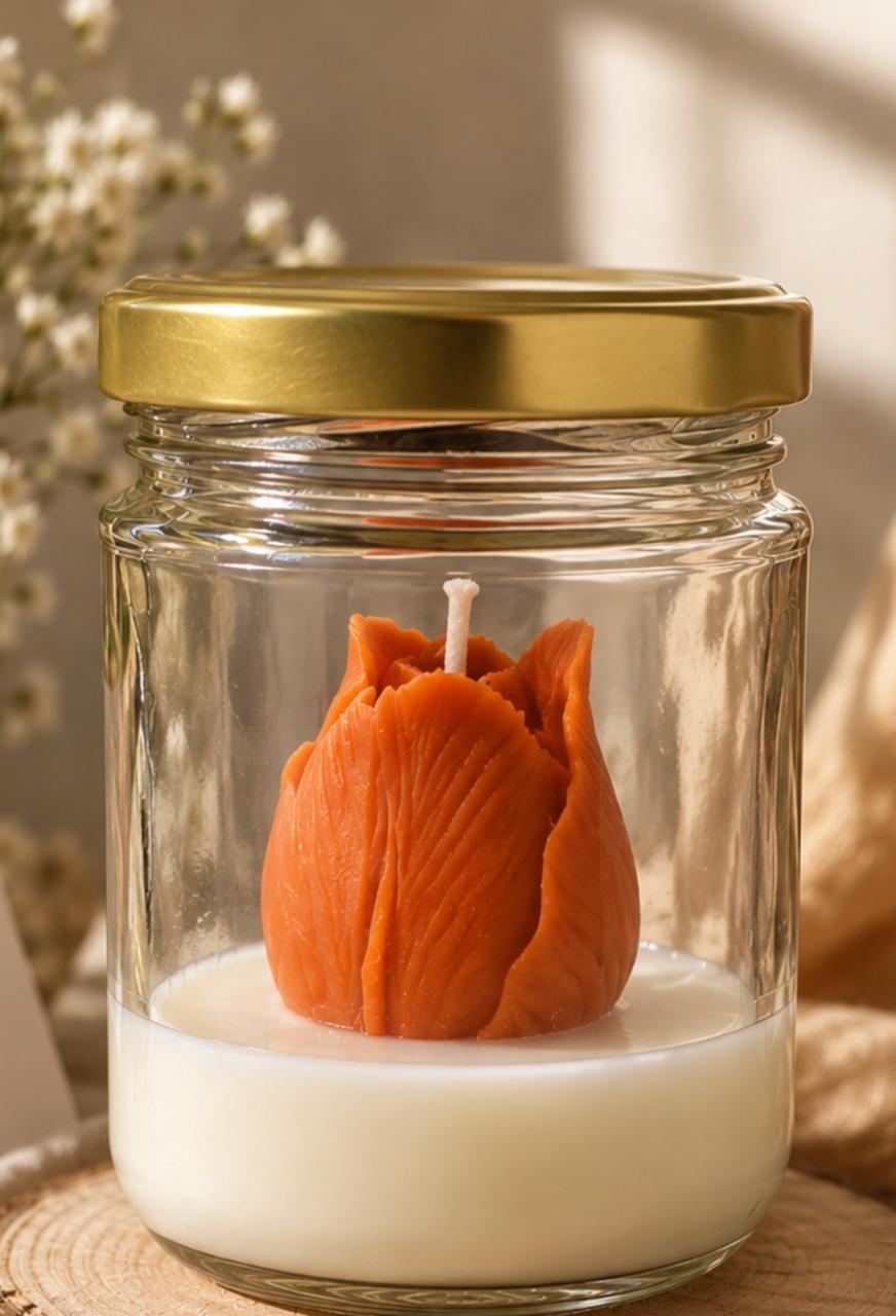 Orange flower-shaped candle in a clear glass jar with a brass lid