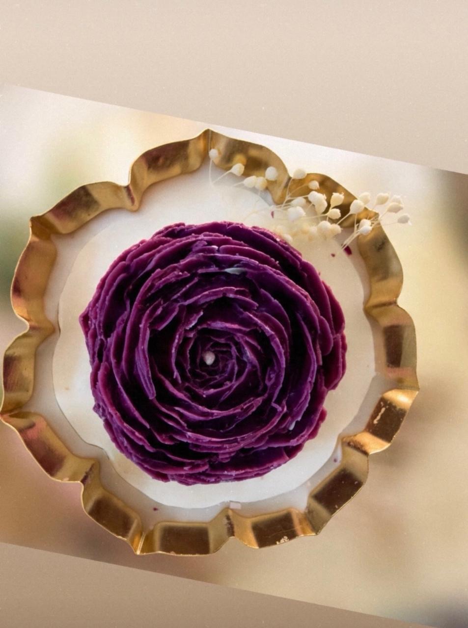 Purple rose candle set in white wax with small dried flowers